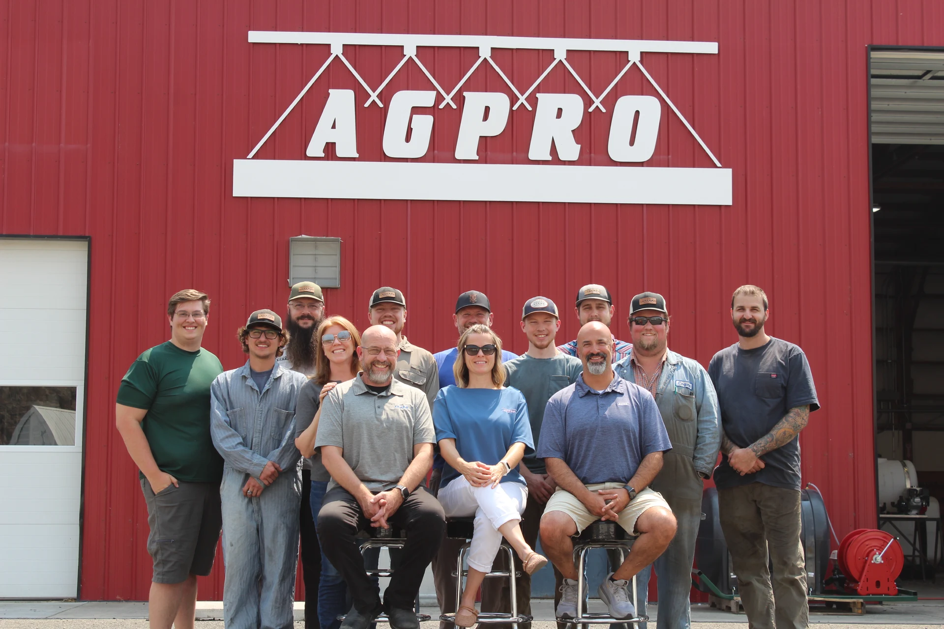 AGPRO staff gathered outside the red shop building beneath the AGPRO sign