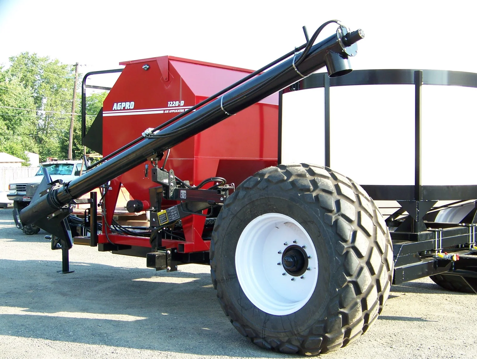 Red AGPRO commodity cart with an air applicator, loading auger, and white liquid tank
