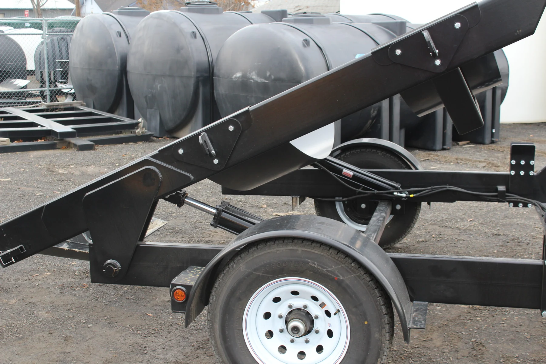 Close view of the tilt trailer’s hydraulic cylinders, tank supports, and steel frame